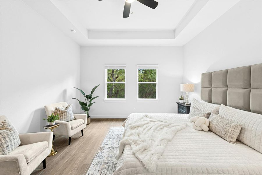Bedroom with tray ceiling, wood finished floors, and a ceiling fan Bedroom with tray ceiling, wood finished floors, and a ceiling fan