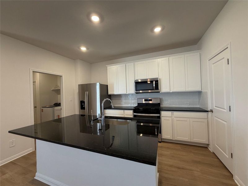 Kitchen with backsplash, appliances with stainless steel finishes, white cabinets, dark wood finished floors, and recessed lighting