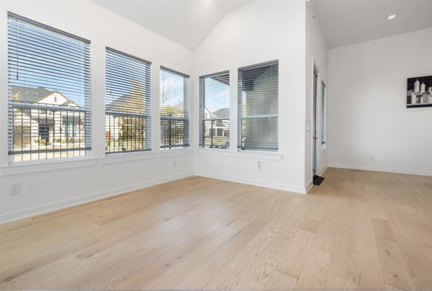 Unfurnished room featuring light wood-style flooring, lofted ceiling, and recessed lighting Unfurnished room featuring light wood-style flooring, lofted ceiling, and recessed lighting