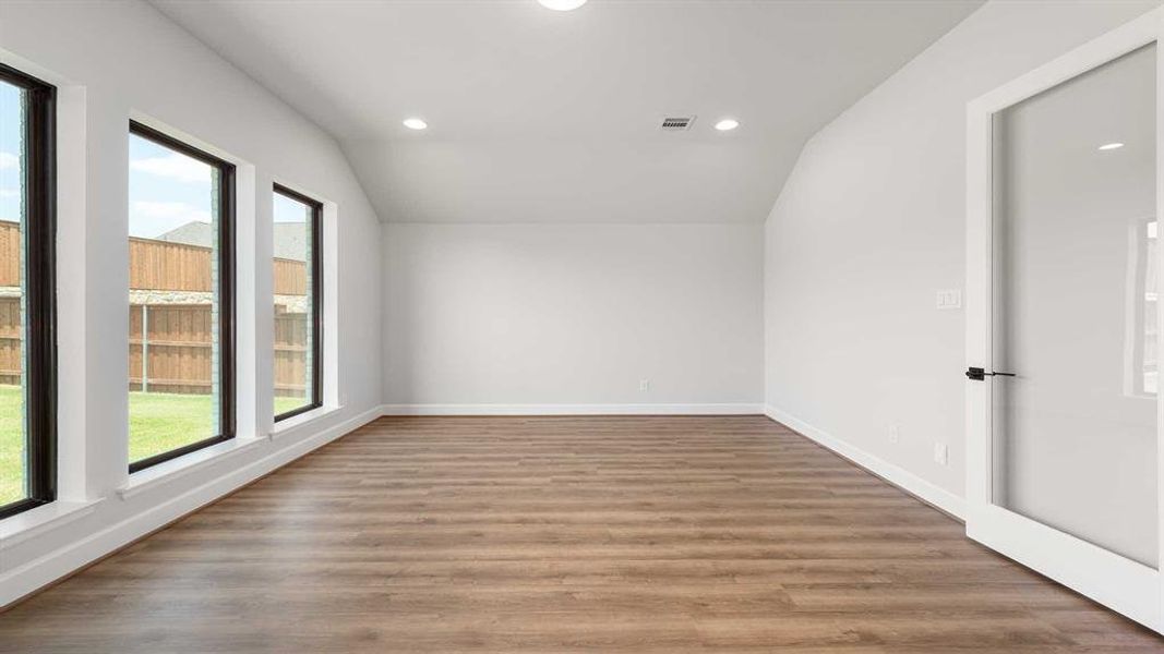 Unfurnished room with lofted ceiling and light hardwood / wood-style flooring