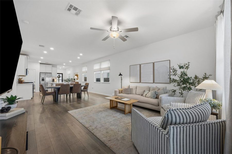 Open-concept living space featuring wood-finish flooring, recessed lighting, a ceiling fan, multiple windows with blinds, and white walls