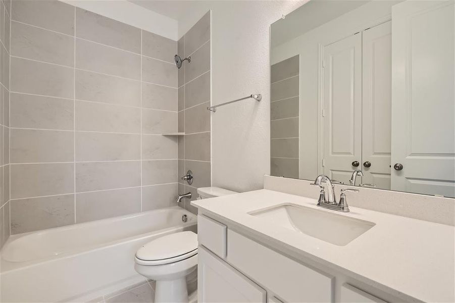 Full bathroom featuring tile flooring, tiled shower / bath combo, toilet, and vanity with extensive cabinet space