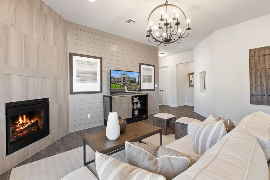 Living room featuring a tiled fireplace, wood finished floors, and a chandelier Living room featuring a tiled fireplace, wood finished floors, and a chandelier