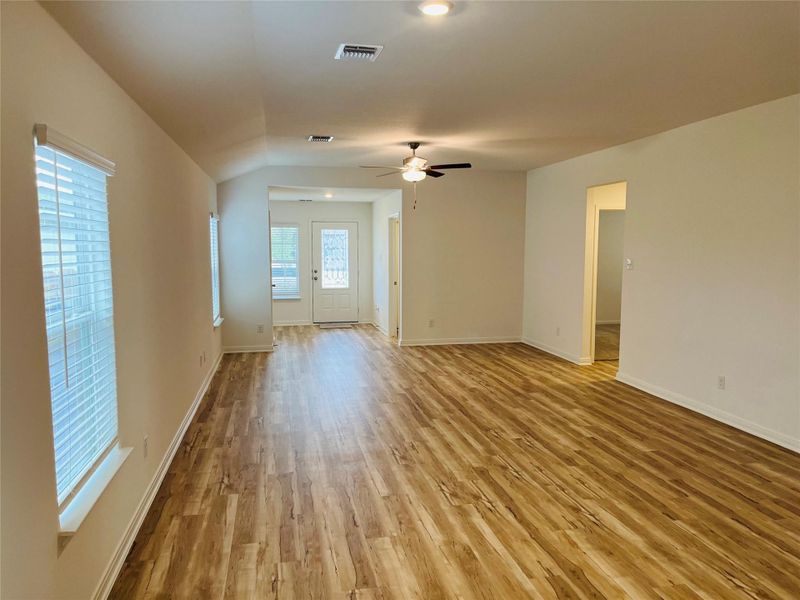 Unfurnished room featuring light wood finished floors, ceiling fan, and vaulted ceiling