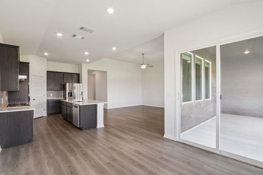 Kitchen with open floor plan, backsplash, a center island with sink, dark wood-type flooring, and appliances with stainless steel finishes Kitchen with open floor plan, backsplash, a center island with sink, dark wood-type flooring, and appliances with stainless steel finishes