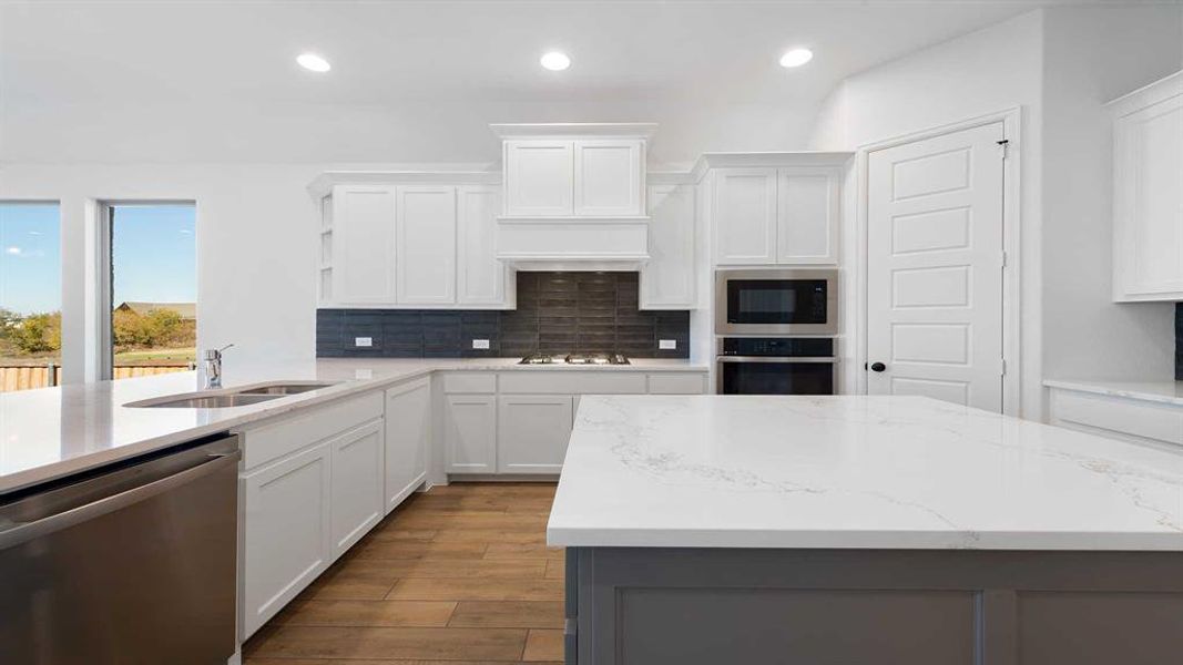 Kitchen featuring light stone counters, stainless steel appliances, sink, light hardwood / wood-style flooring, and white cabinetry