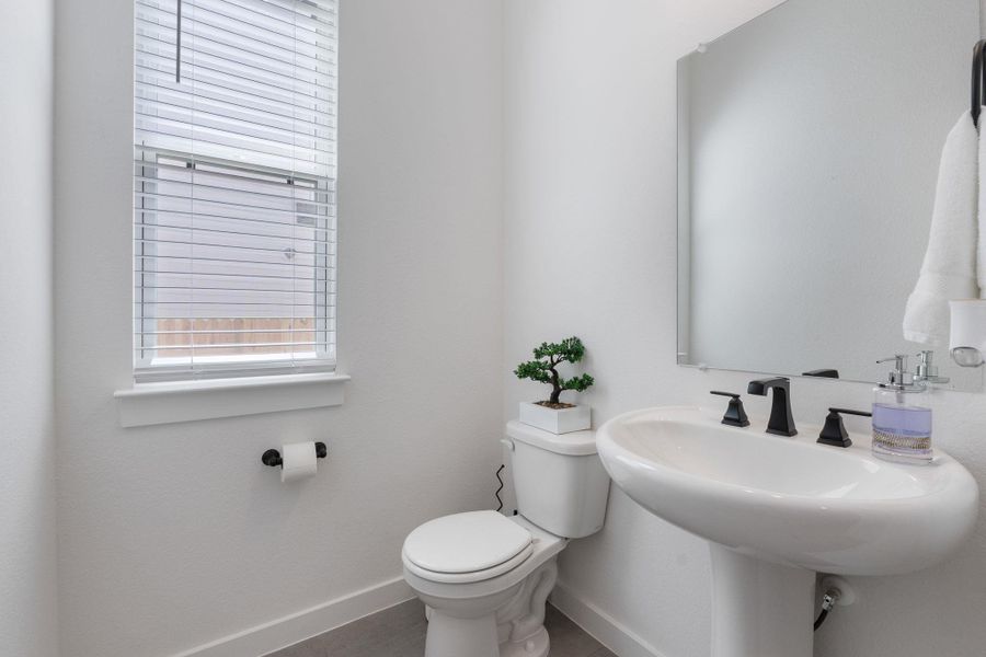 Half bathroom with toilet, baseboards, and a sink