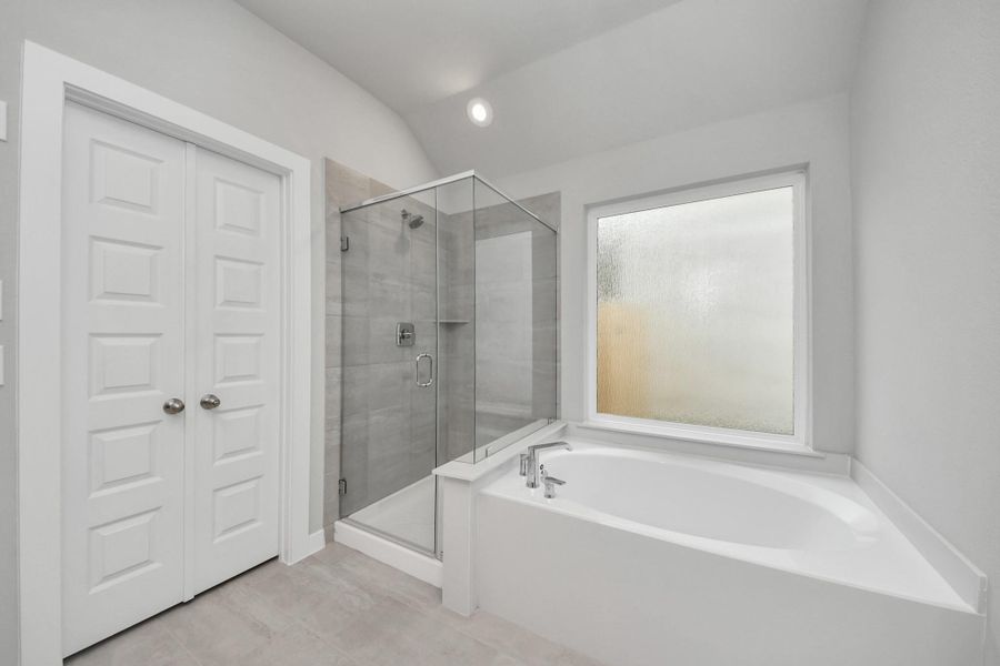 Escape to a spa-like oasis in this primary bathroom. Enjoy a walk-in shower with tile surround, a separate garden tub with custom detailing, and an elegant vanity featuring light countertops, modern hardware, and beautiful recessed lights. Experience luxury and relaxation in every detail.