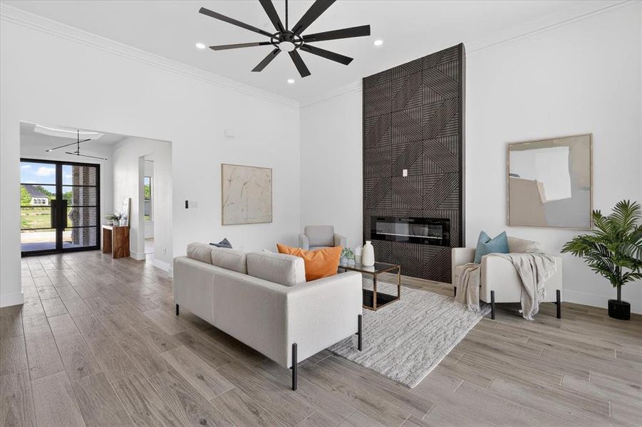 Living room featuring ornamental molding, light wood finished floors, a large fireplace, a ceiling fan, and recessed lighting