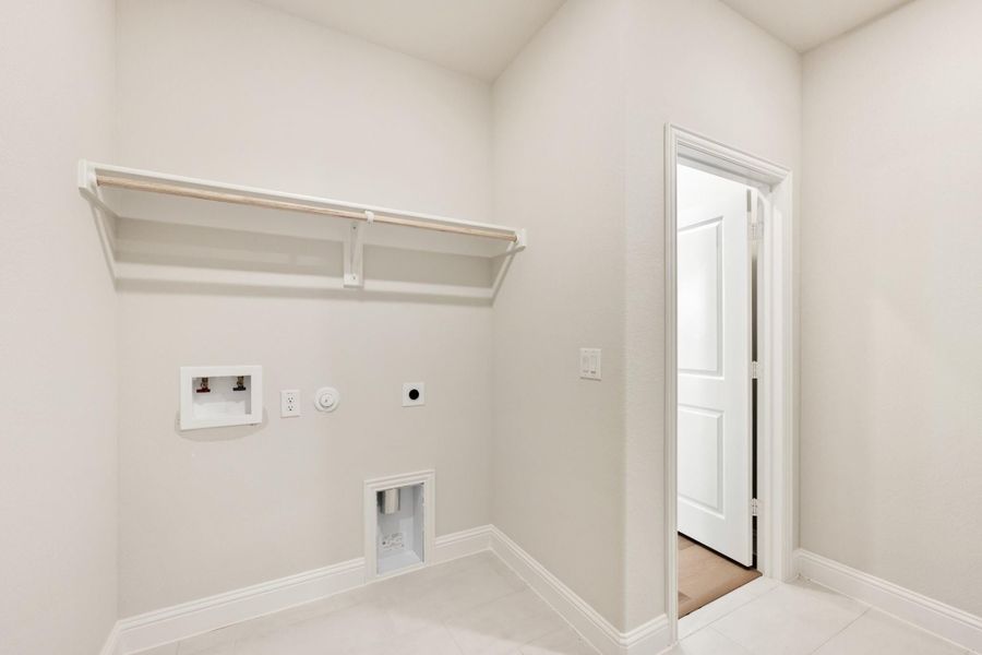 Laundry room with wall-mounted shelf, washer and dryer hookups, and open white door