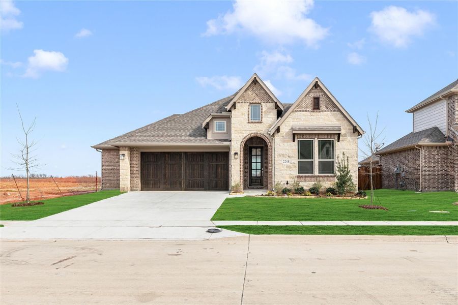 Single-story home with stone and brick exterior, two-car garage, arched entry, and green front lawn Single-story home with stone and brick exterior, two-car garage, arched entry, and green front lawn