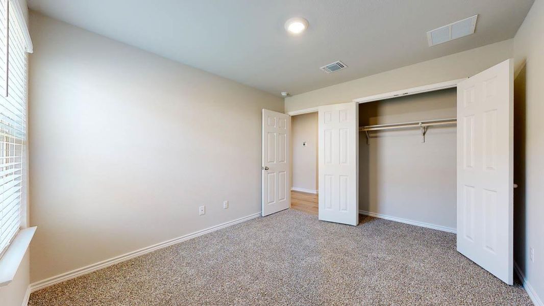 Unfurnished bedroom featuring light colored carpet, a closet, and multiple windows