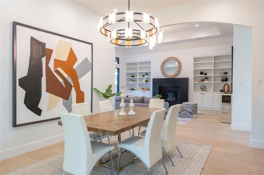 Dining space with light hardwood / wood-style floors, a chandelier, and built in shelves