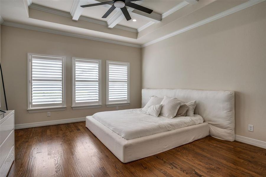 Bedroom with coffered ceiling, ceiling fan, crown molding, dark wood-type flooring, and beam ceiling