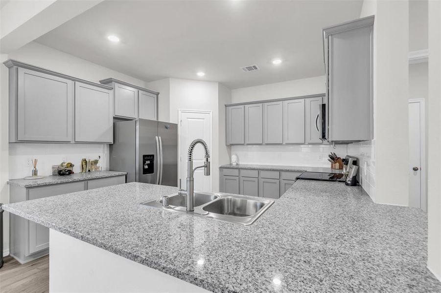 Kitchen featuring stainless steel appliances, gray cabinets, a sink, a peninsula, and recessed lighting Kitchen featuring stainless steel appliances, gray cabinets, a sink, a peninsula, and recessed lighting