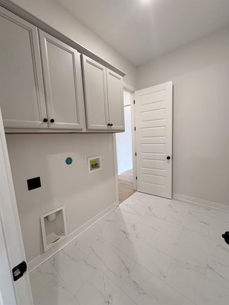 White shaker-style cabinetry with black hardware, plank-style flooring, white walls, and a white paneled door White shaker-style cabinetry with black hardware, plank-style flooring, white walls, and a white paneled door