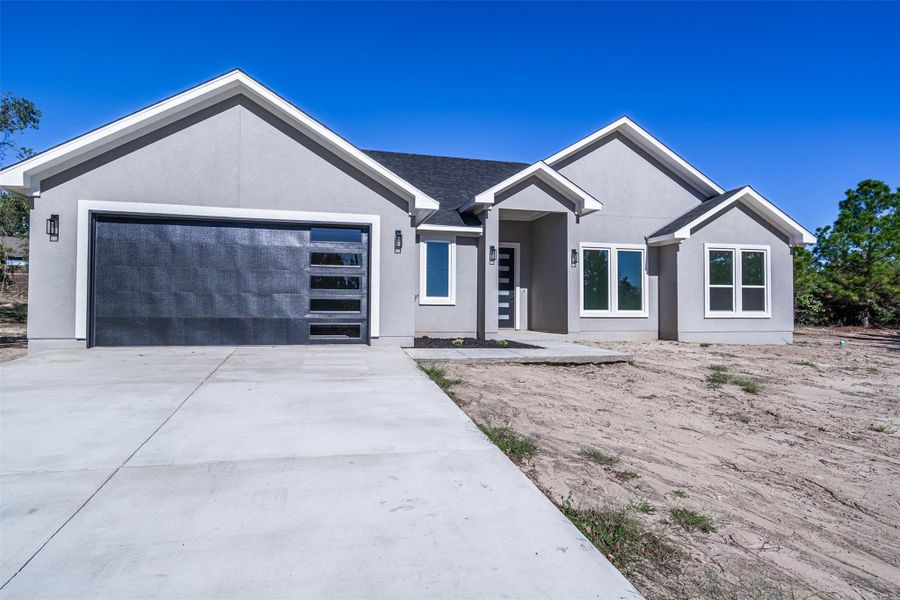 View of front of home with a garage, stucco siding, and concrete driveway