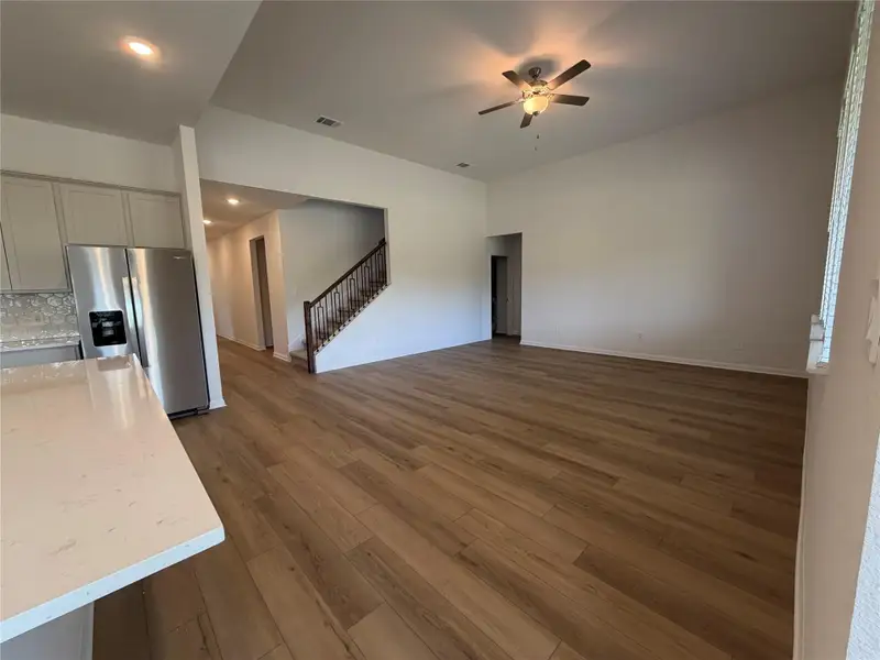Unfurnished living room with dark wood-style floors, ceiling fan, stairs, and recessed lighting