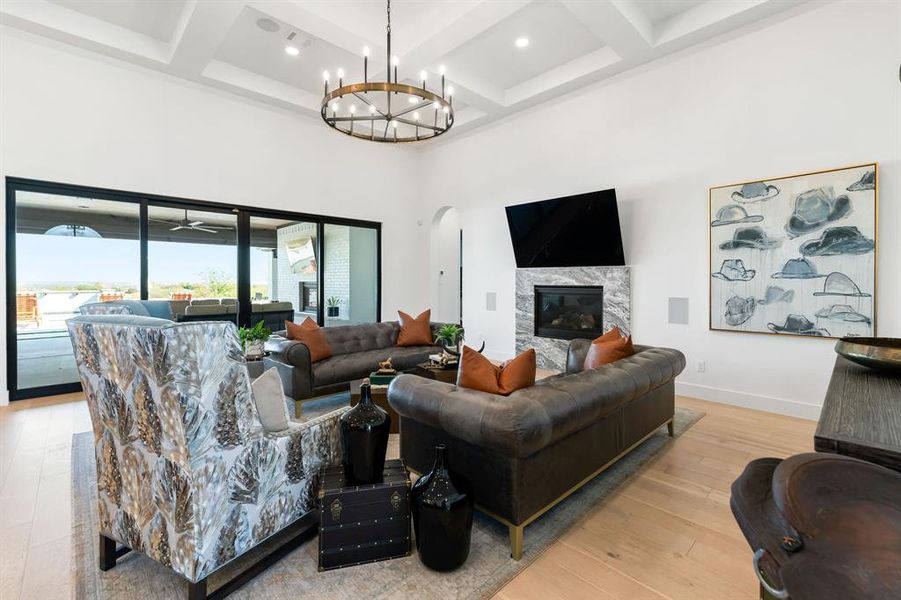 Living room featuring a towering ceiling, coffered ceiling, arched walkways, a premium fireplace, and beamed ceiling Living room featuring a towering ceiling, coffered ceiling, arched walkways, a premium fireplace, and beamed ceiling
