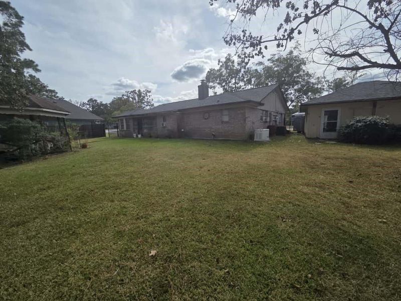 Back of house with a chimney, a lawn, and brick siding Back of house with a chimney, a lawn, and brick siding