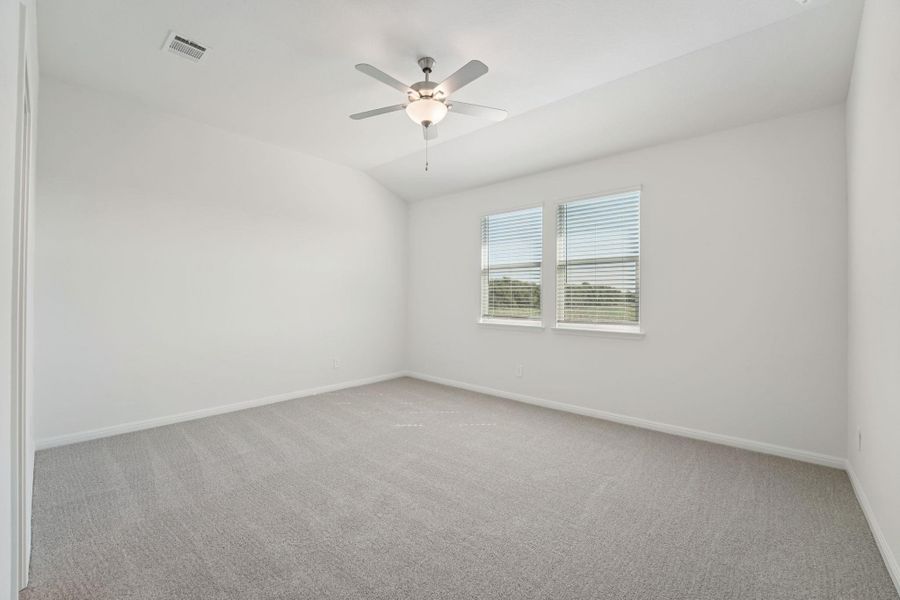 Spare room featuring light colored carpet, lofted ceiling, and a ceiling fan
