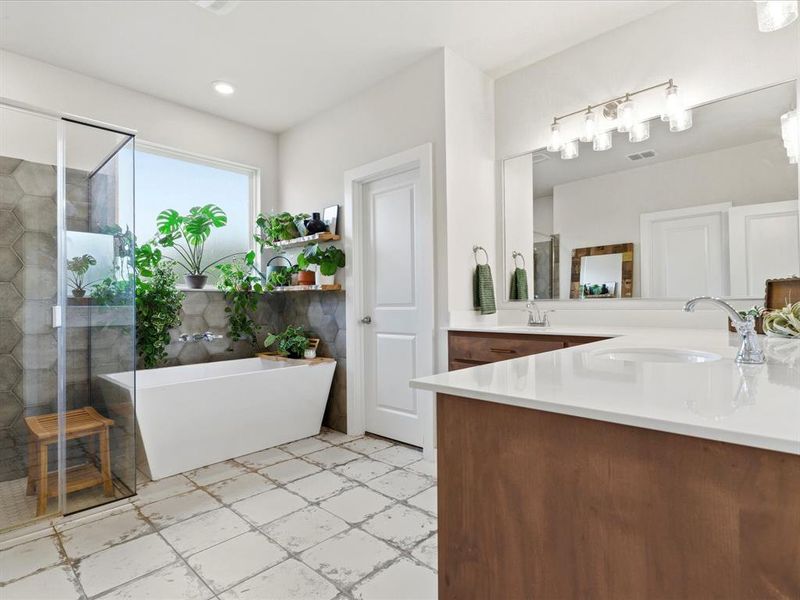 Primary bathroom featuring dual vanities, soaking tub, and separate shower.
