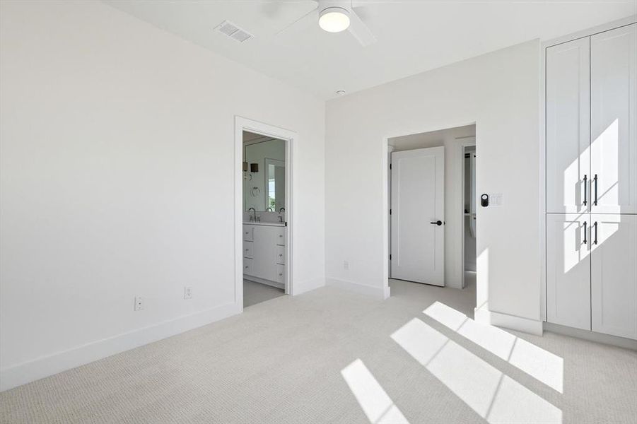 Unfurnished bedroom with light colored carpet, ensuite bathroom, and a ceiling fan Unfurnished bedroom with light colored carpet, ensuite bathroom, and a ceiling fan