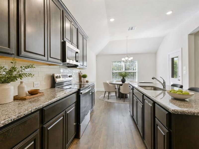 Kitchen featuring dark wood-finish cabinetry, light speckled countertops, a subway tile backsplash, and stainless steel appliances
