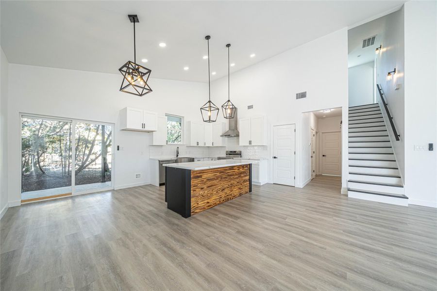 Kitchen with white cabinets, open floor plan, a high ceiling, a kitchen island, and decorative light fixtures
