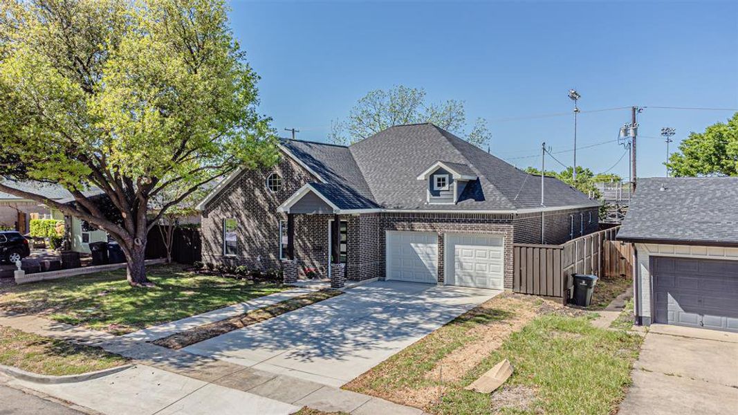 The property features a brick exterior, a driveway, and an attached two-car garage