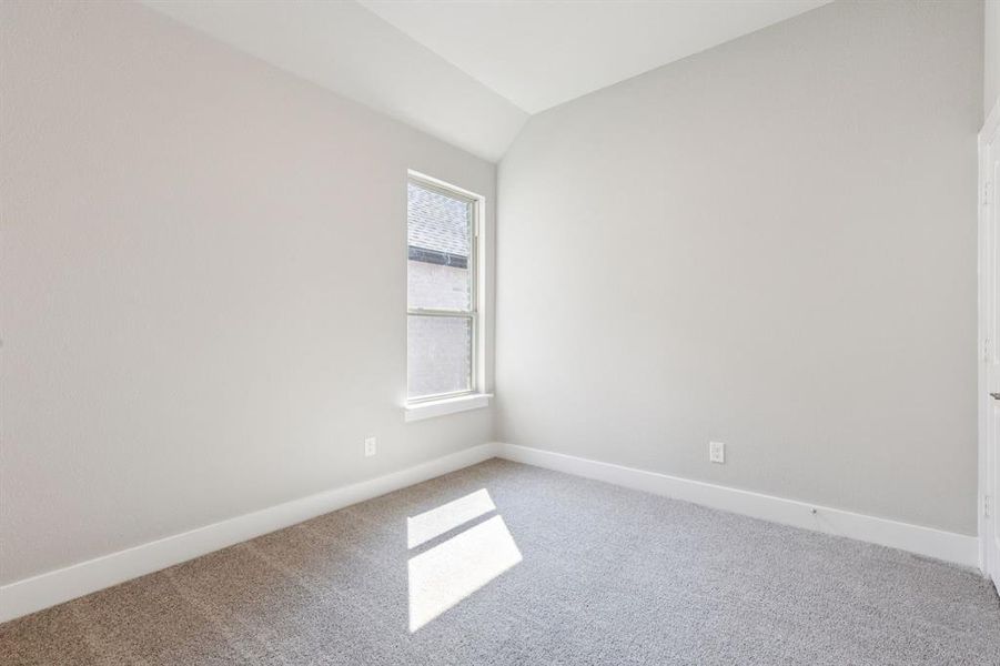Carpeted spare room with lofted ceiling and baseboards