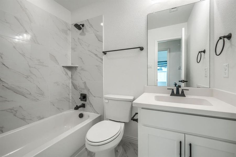 Bathroom featuring marble finish floor, toilet, vanity, and  shower combination