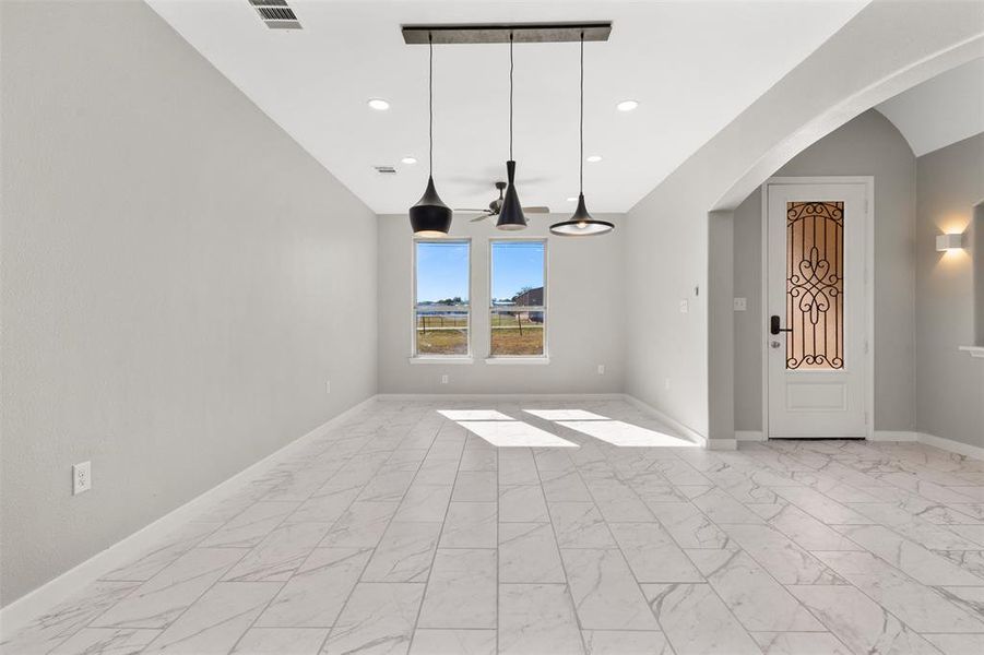 Spare room with light marble finish floors, arched walkways, and recessed lighting