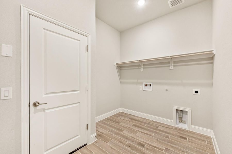 Laundry room with wood-look tile floor, wall shelf, and washer and dryer hookups