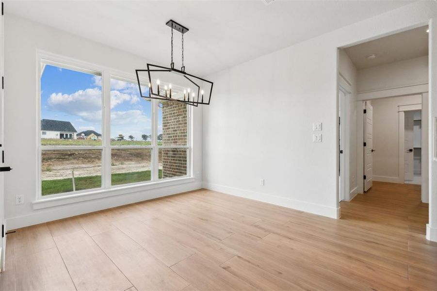 Unfurnished dining area featuring a chandelier and light hardwood / wood-style floors