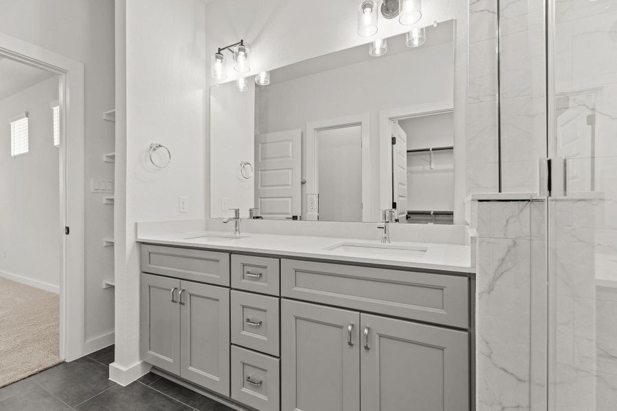 Dual vanities with sleek cabinetry create a functional and elegant primary bathroom. Dual vanities with sleek cabinetry create a functional and elegant primary bathroom.