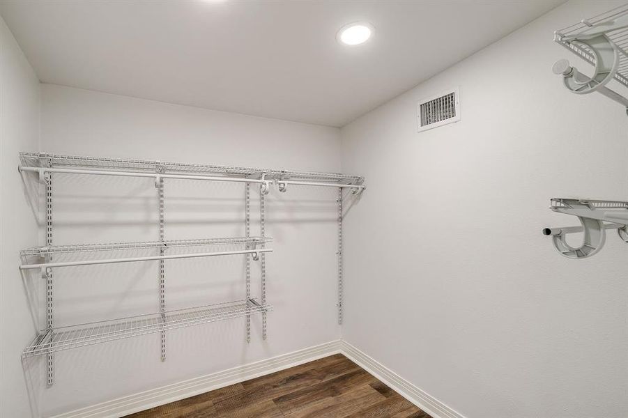 Spacious closet featuring dark wood-type flooring and recessed lighting