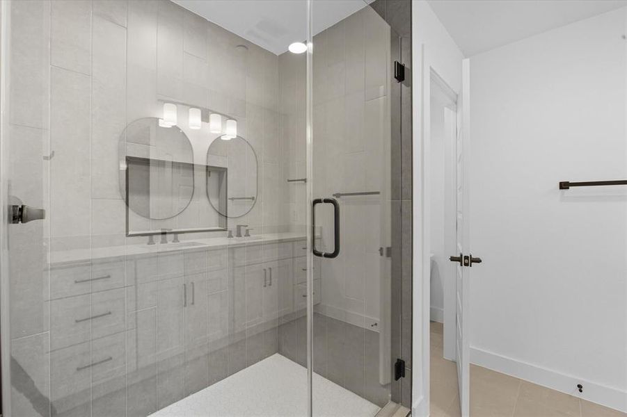 Full bathroom featuring a stall shower, tile patterned floors, and double vanity