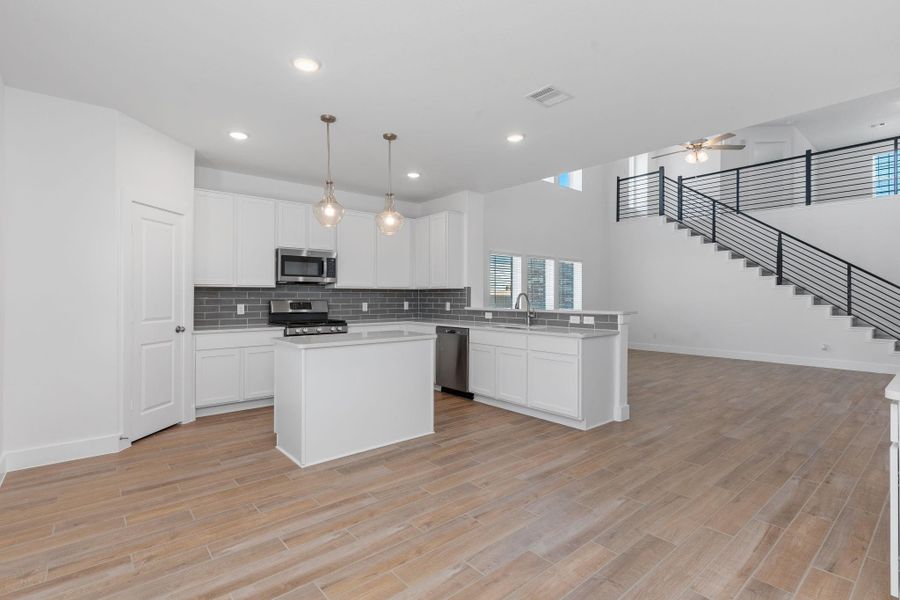This wide-open view showcases the dramatic architecture of the home, including soaring two-story ceilings, a sweeping modern iron staircase, and an open layout that connects the kitchen to the living area. It’s an ideal setup for both everyday comfort and unforgettable entertaining. This wide-open view showcases the dramatic architecture of the home, including soaring two-story ceilings, a sweeping modern iron staircase, and an open layout that connects the kitchen to the living area. It’s an ideal setup for both everyday comfort and unforgettable entertaining.
