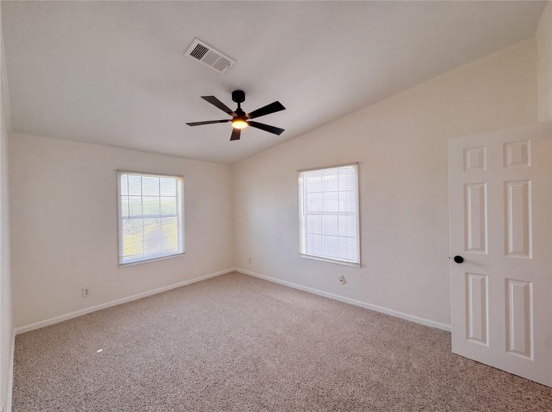 Vaulted ceilings and neutral carpeting define this airy bedroom space.