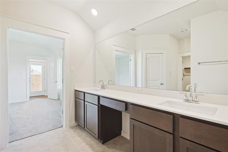 Bathroom featuring vanity, lofted ceiling, and tile patterned flooring