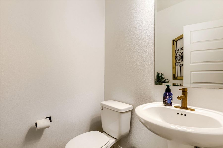 A compact powder room with a sleek pedestal sink and contemporary brass faucet. A compact powder room with a sleek pedestal sink and contemporary brass faucet.