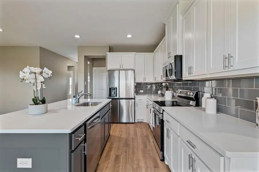 Kitchen featuring white cabinets, stainless steel appliances, a kitchen island with sink, and sink