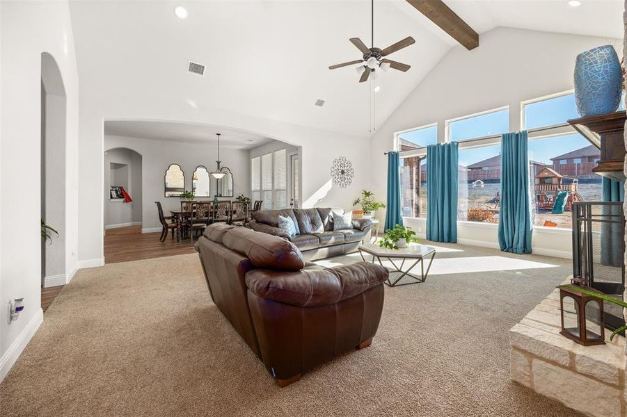 Carpeted living room with beamed ceiling, high vaulted ceiling, and ceiling fan Carpeted living room with beamed ceiling, high vaulted ceiling, and ceiling fan