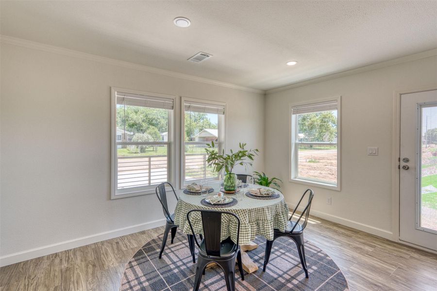Recessed lighting illuminates this dining area with wood-look flooring and multiple windows framing exterior views. Recessed lighting illuminates this dining area with wood-look flooring and multiple windows framing exterior views.