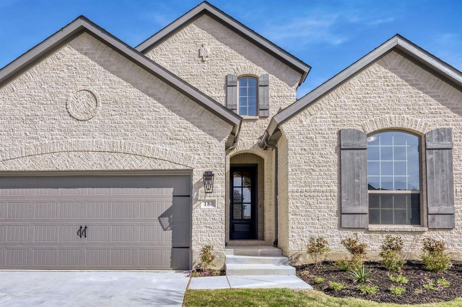 French provincial home featuring concrete driveway, an attached garage, and stone siding