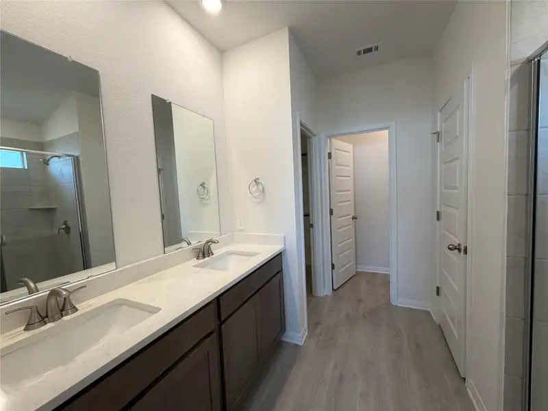 Bathroom featuring a shower stall, light wood-type flooring, and double vanity