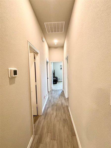 Hall featuring light wood-type flooring and a textured wall Hall featuring light wood-type flooring and a textured wall