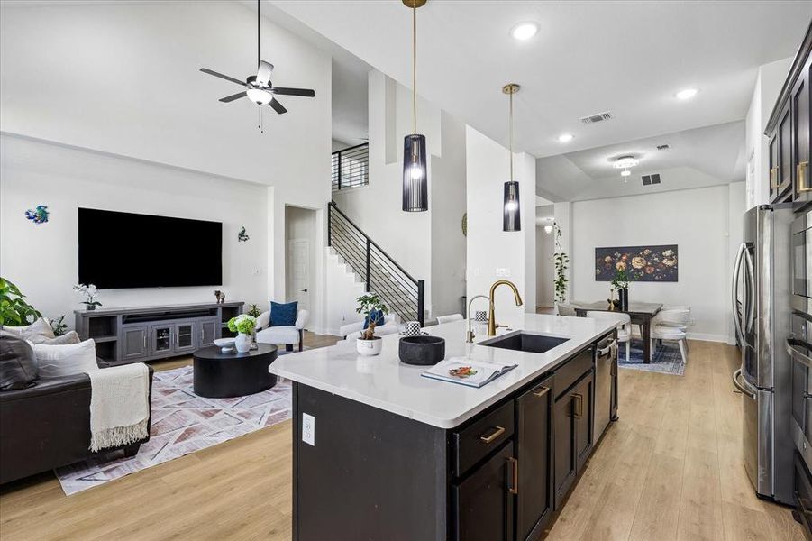 Open-concept living space featuring a modern kitchen island with white countertop, recessed lighting, and wood-finish flooring Open-concept living space featuring a modern kitchen island with white countertop, recessed lighting, and wood-finish flooring