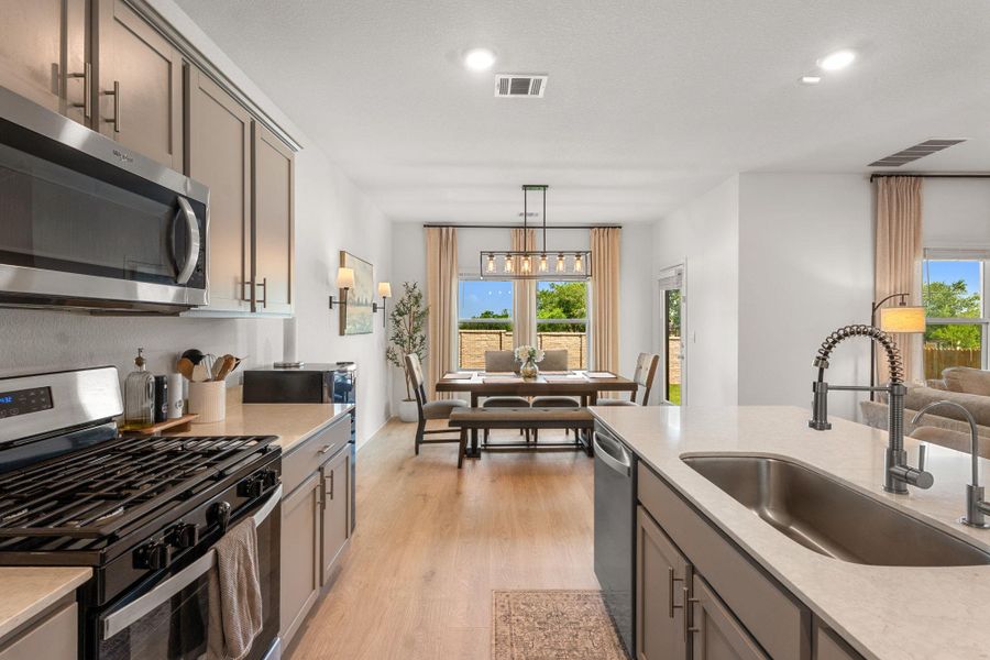 A well-equipped kitchen flows seamlessly into a dining area, featuring sleek cabinetry and a gas range. A well-equipped kitchen flows seamlessly into a dining area, featuring sleek cabinetry and a gas range.